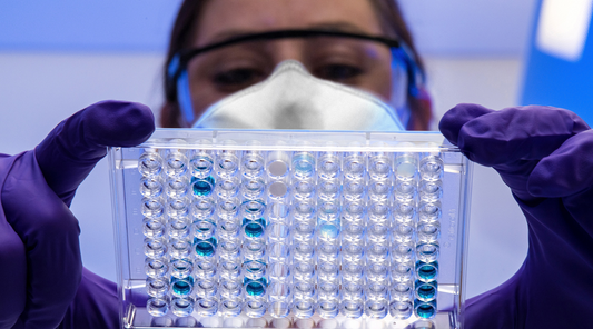 A worker meticulously inspecting products for quality assurance in a laboratory setting