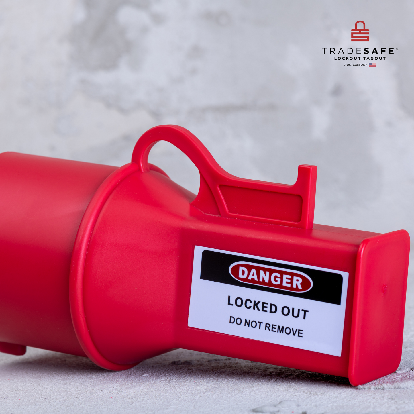 eye-level slanted view of a pin & sleeve socket lockout device lying down on a concrete floor