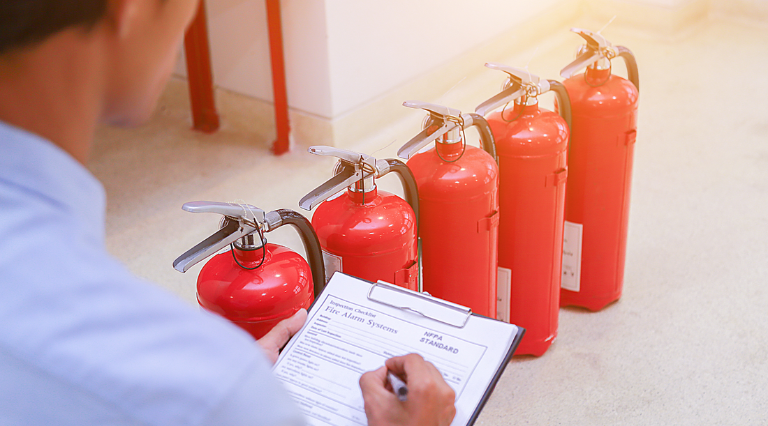 person with a clipboard inspecting fire extinguishers