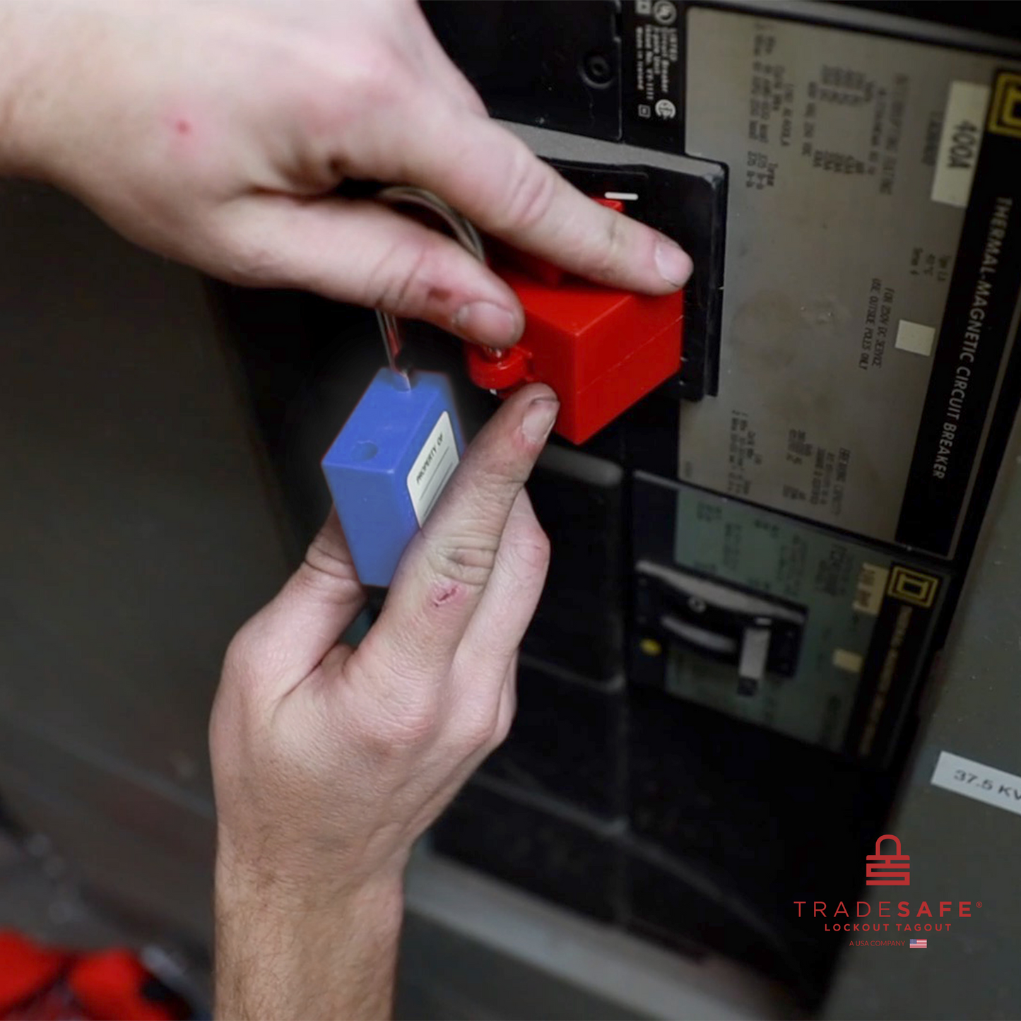 a blue loto padlock being inserted in a clamp-on circuit breaker lock