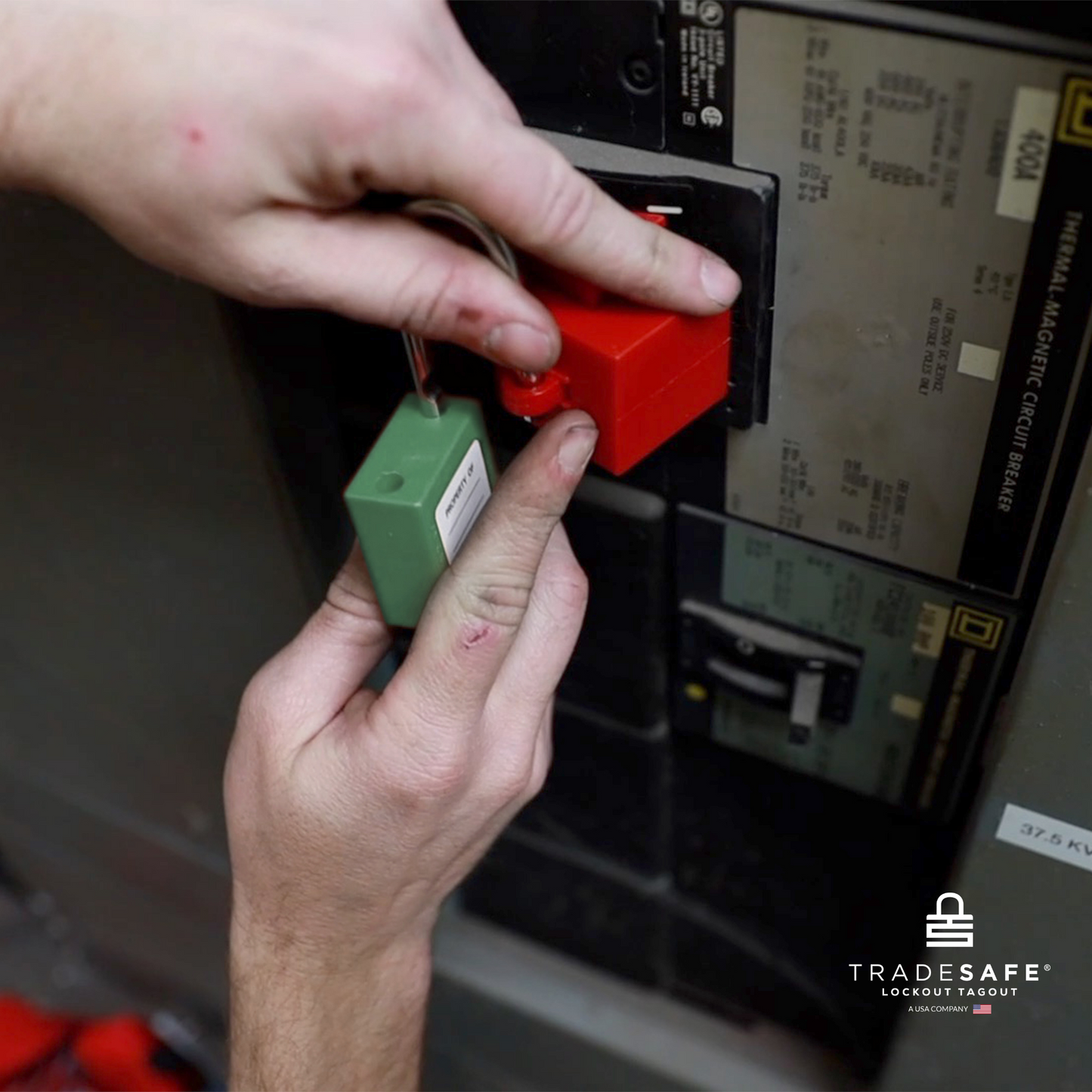 a green loto padlock being inserted in a clamp-on circuit breaker lock