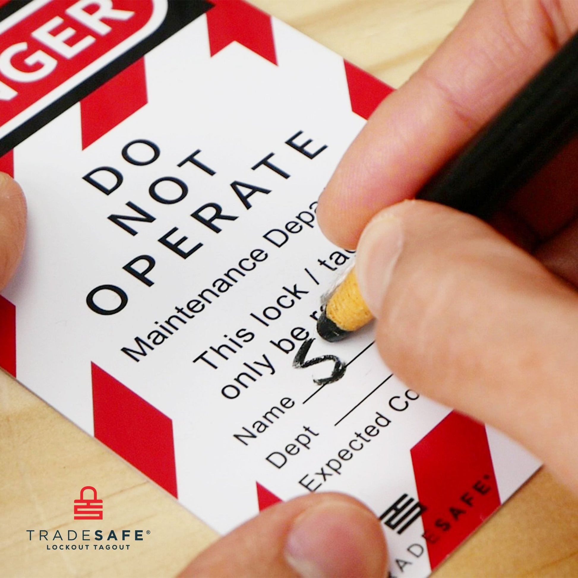 top view of a hand writing on a loto safety tag using a black wax pencil