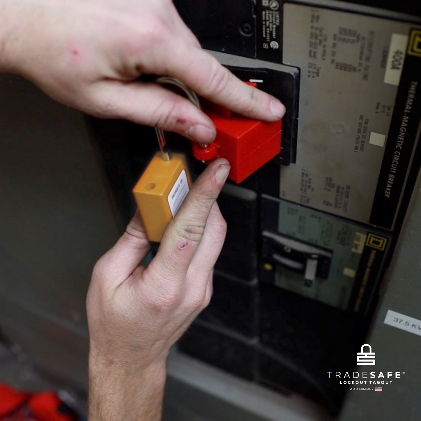 a orange loto padlock being inserted in a clamp-on circuit breaker lock