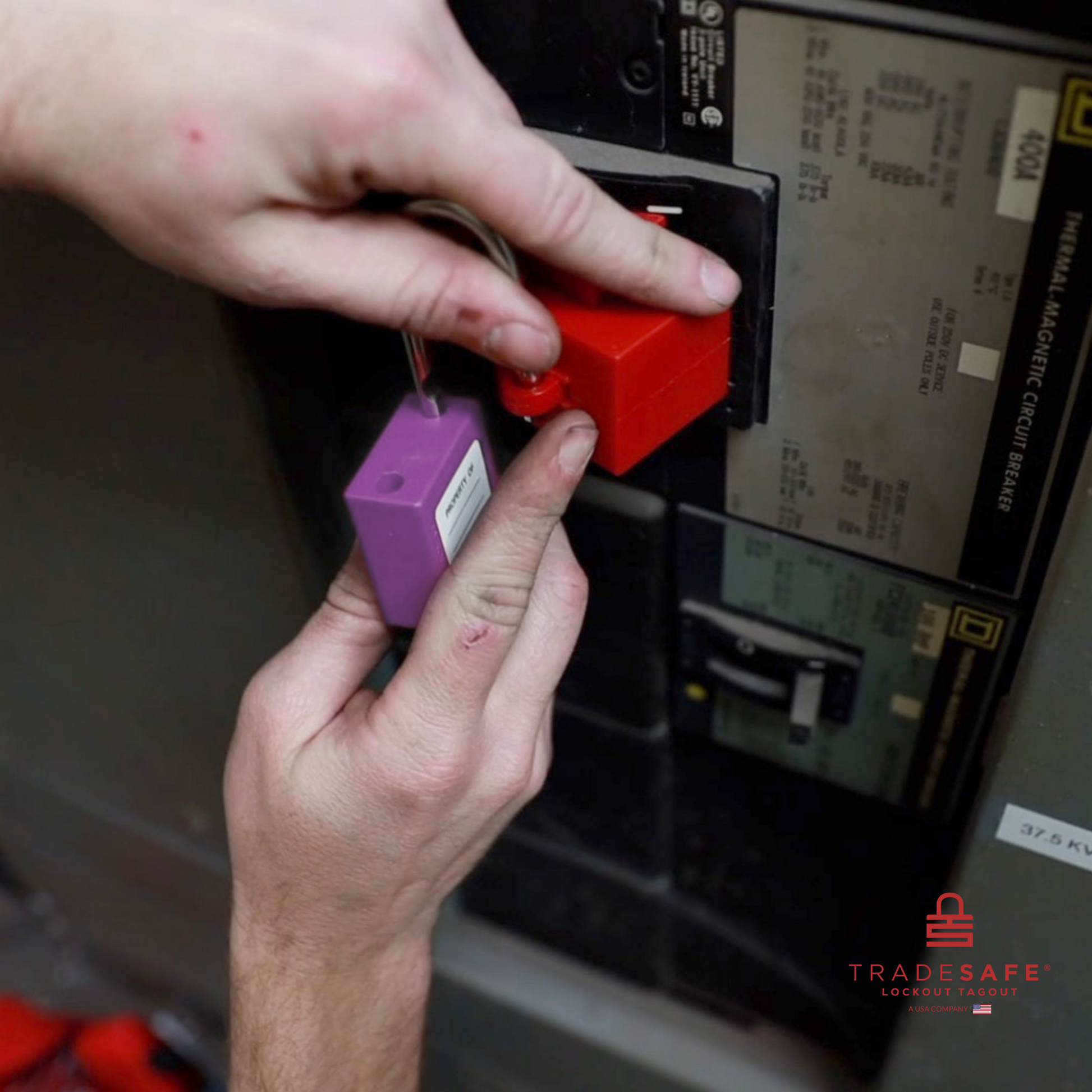 a purple loto padlock being inserted in a clamp-on circuit breaker lock 