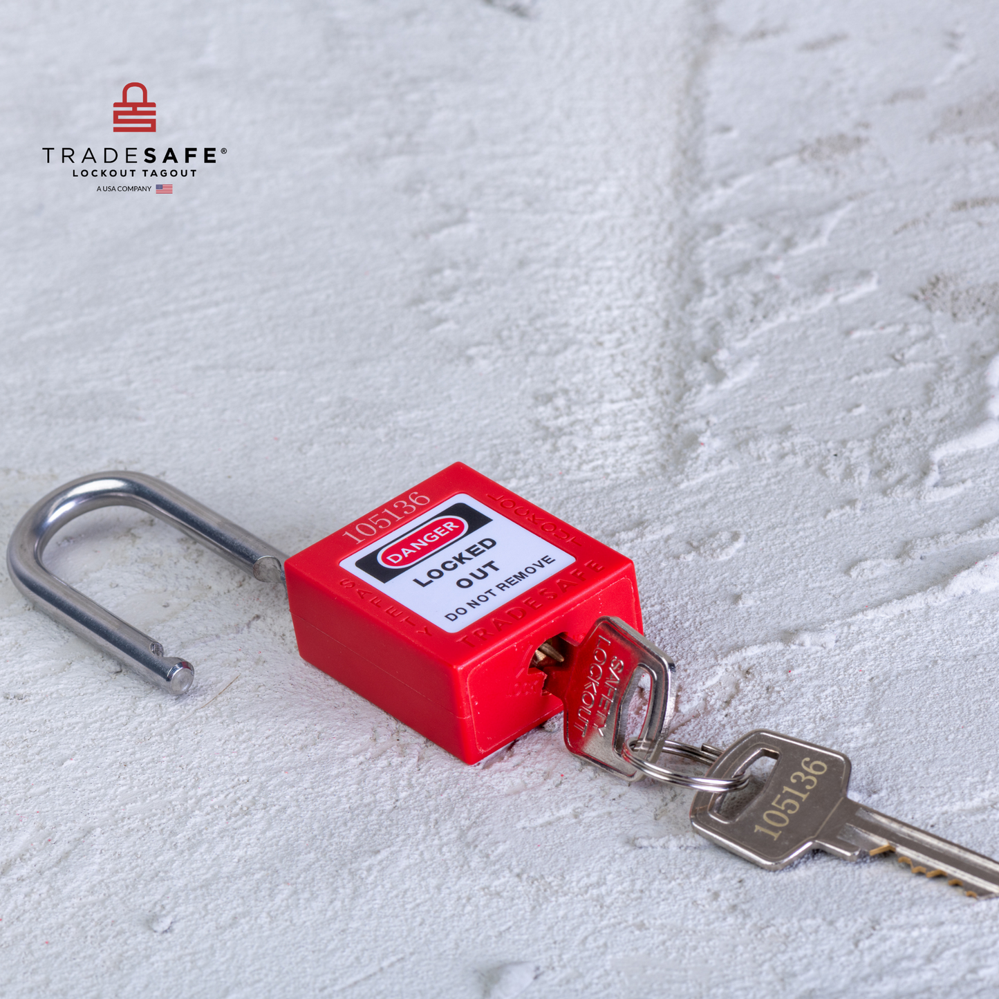 a red loto padlock with 2 keys, 1 key inserted, lying down in a concrete floor