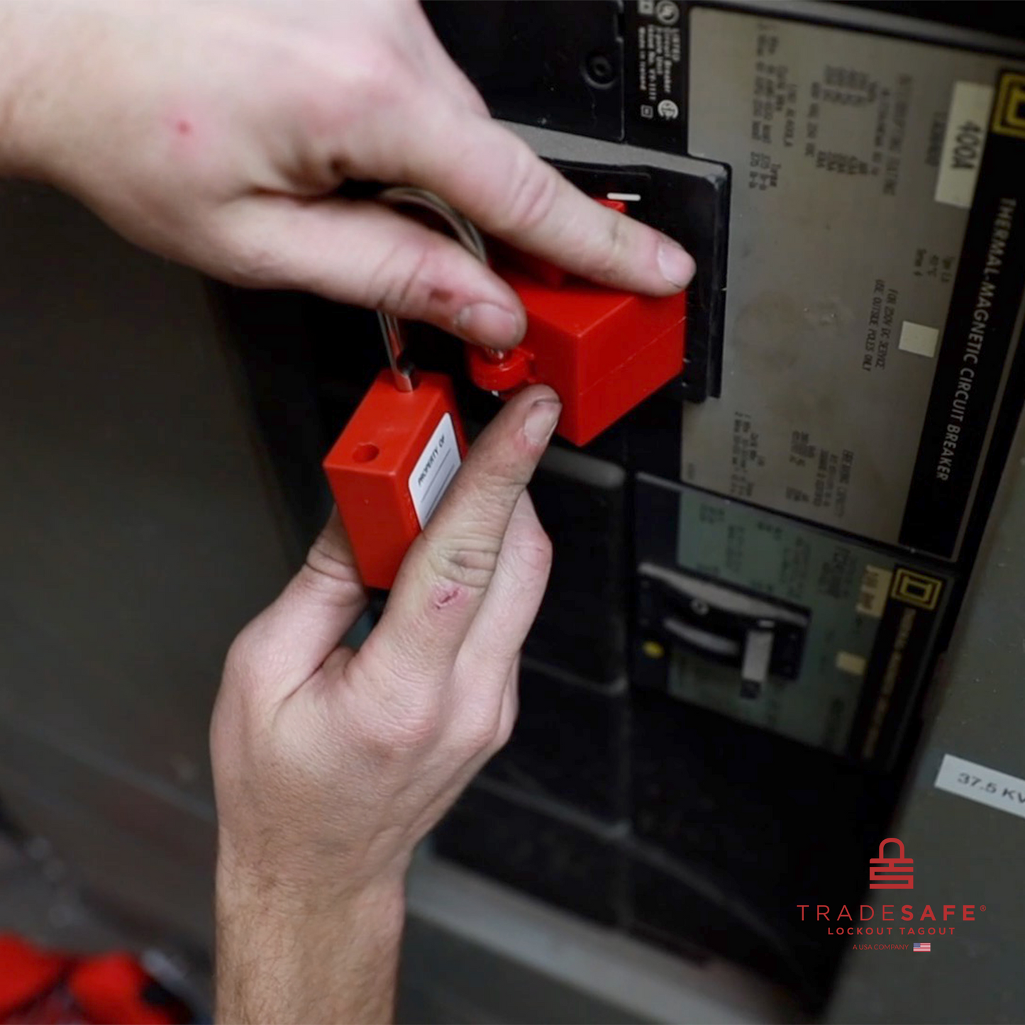 a red loto padlock being inserted in a clamp-on circuit breaker lock