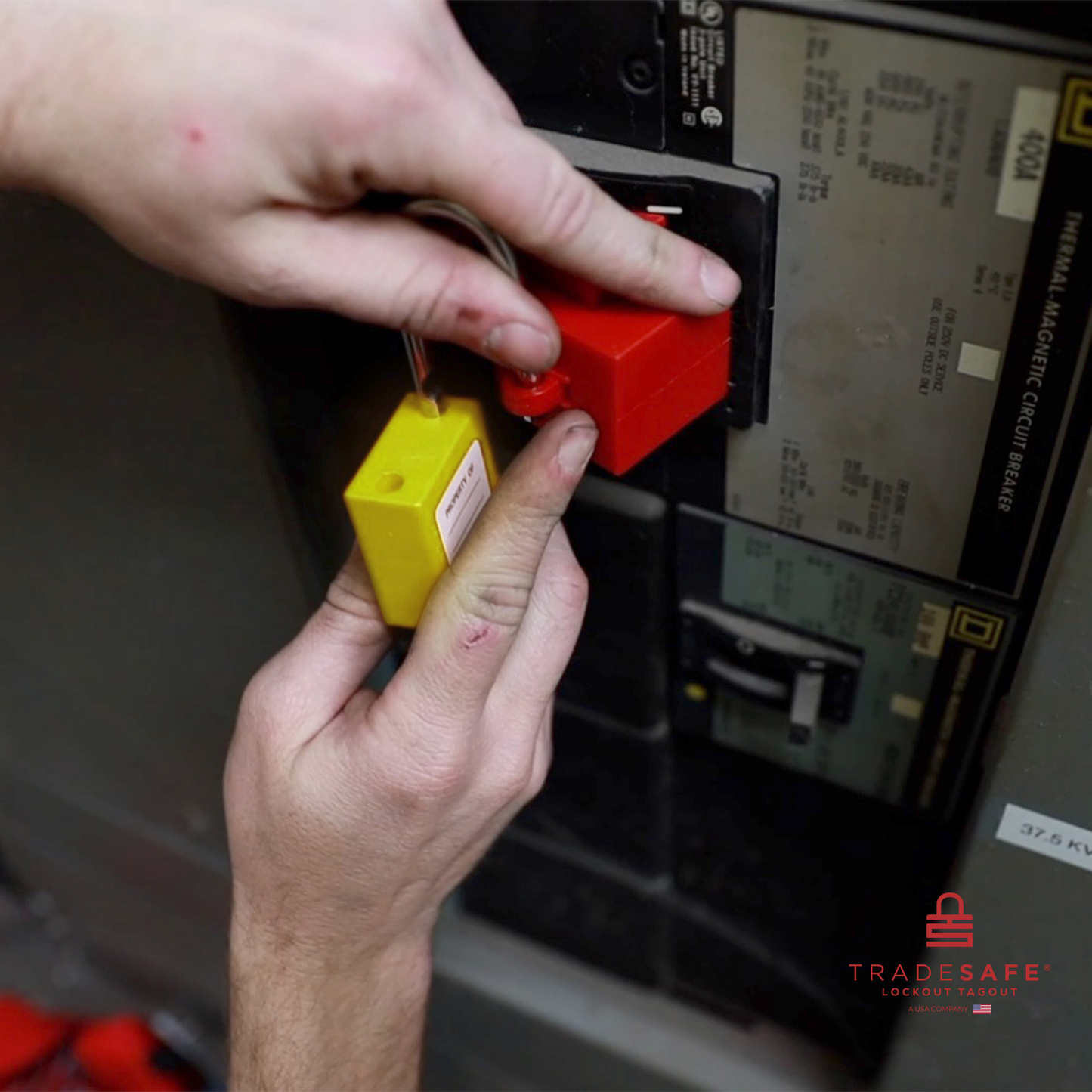 a yellow loto padlock being inserted in a clamp-on circuit breaker lock