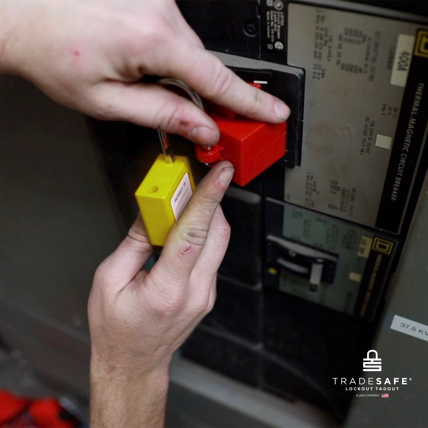 a yellow loto padlock being inserted in a clamp-on circuit breaker lock