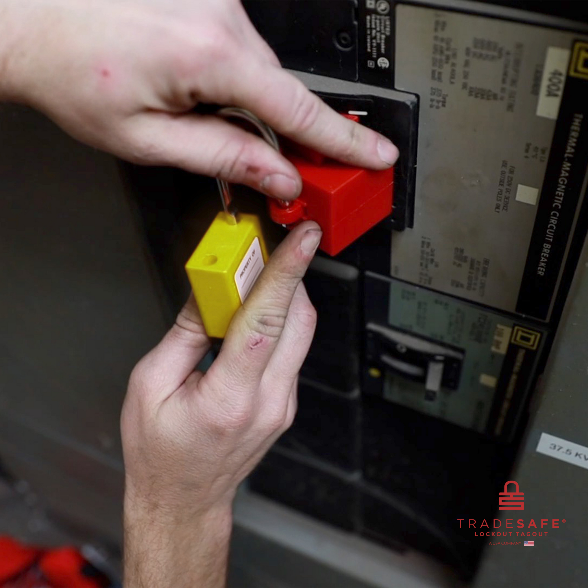 a yellow loto padlock being inserted in a clamp-on circuit breaker lock 